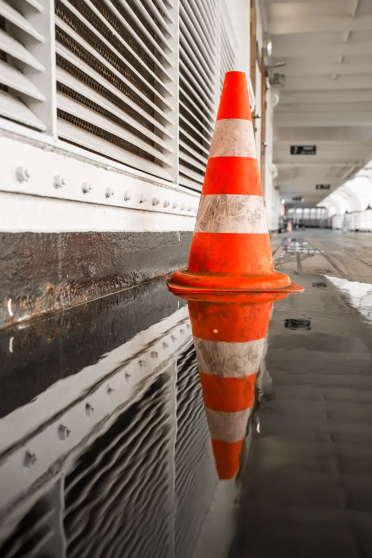 Cono de señalización junto a un charco en una zona común de edificio