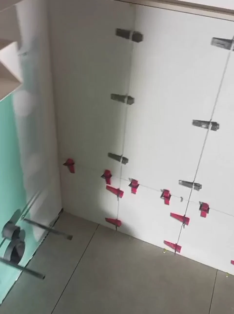 Azulejos colocados en pared con calzos de nivelación en reforma de local en Tarragona